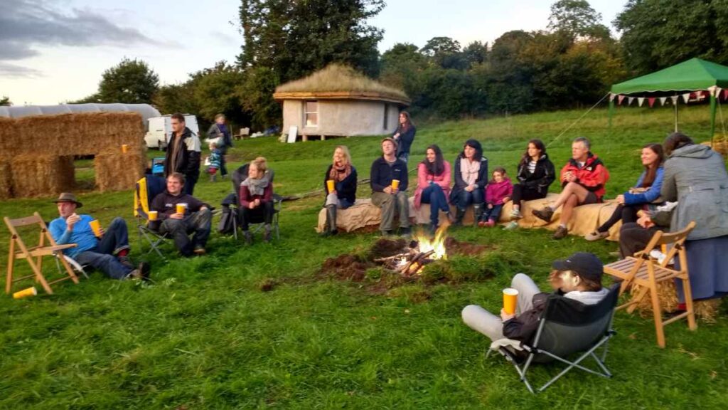 People sitting around the fire, SCA's Roundhouse in the background